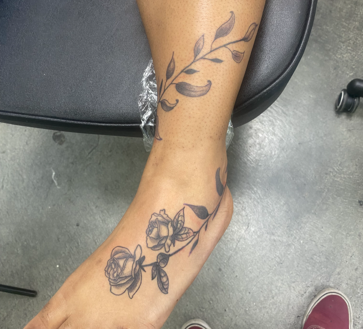 Person's leg with floral tattoos on a chair and floor background