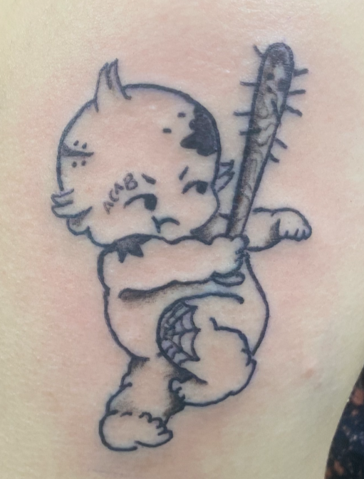 Tattoo of a cute baby swinging a bat with nails in it